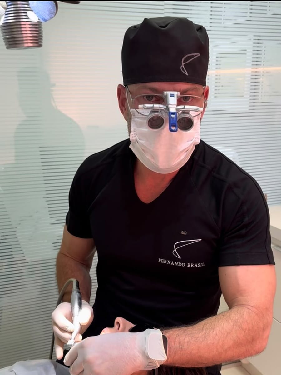 Dr. Fernando Brasil de lupa e uniforme com a sua marca, durante um atendimento